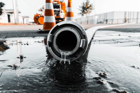A selective closeup shot of a gray pipe with water coming out its hole